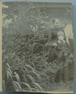 Image of Two women [partial] and young boy [face damaged] in garden